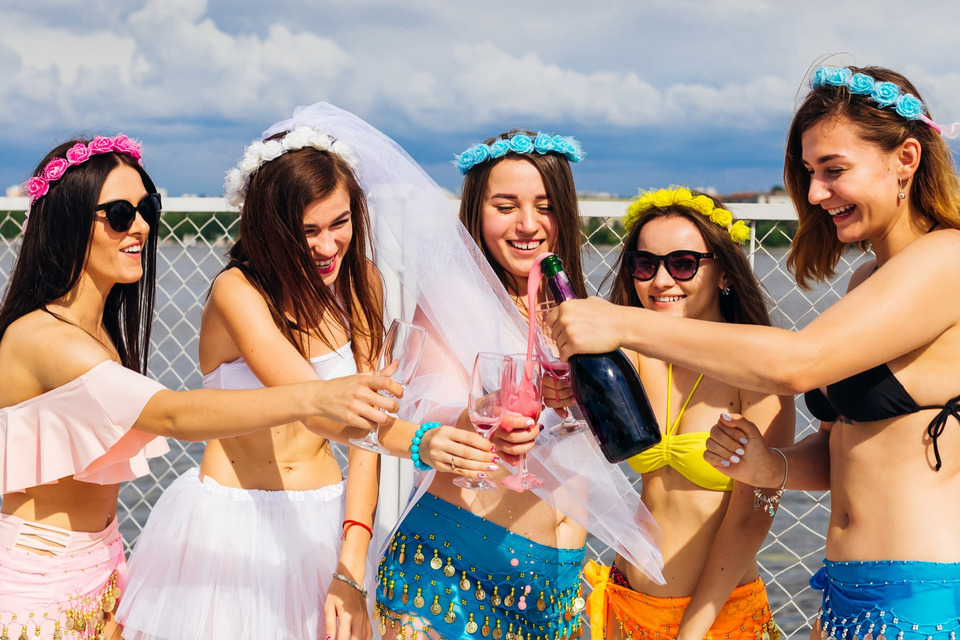 Młode kobiety w strojach kąpielowych otwierają szampana na wieczorze panieńskim